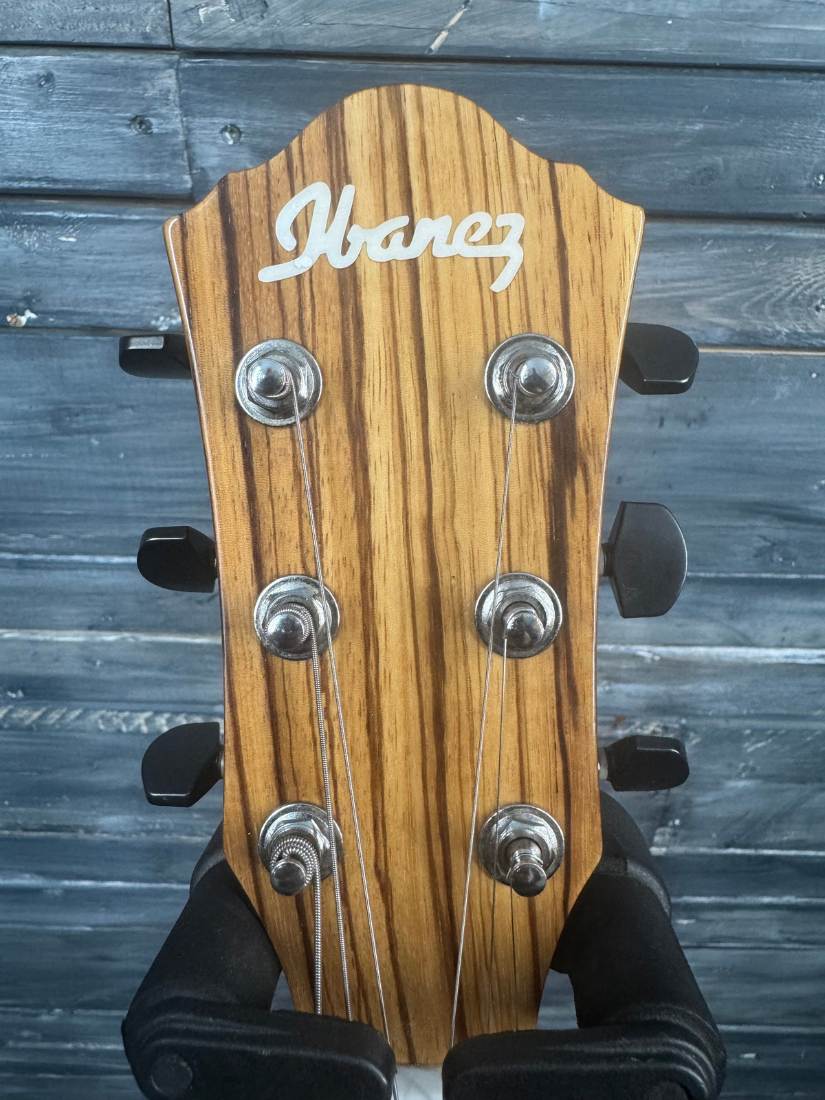 Close-up of a guitar headstock with brand name on a wooden background