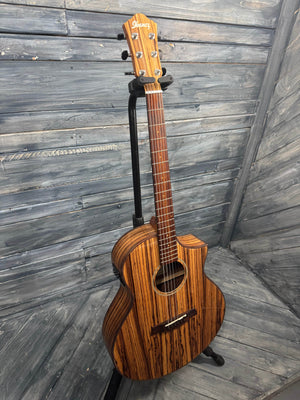 Wooden acoustic guitar on a stand against a wooden background