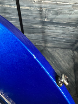 Close-up of a blue object with a screw on a wooden background