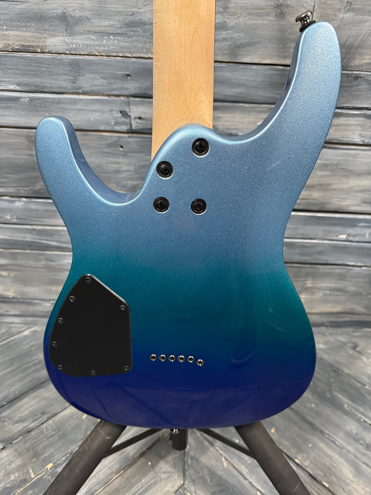Blue electric guitar on a stand against a wooden background