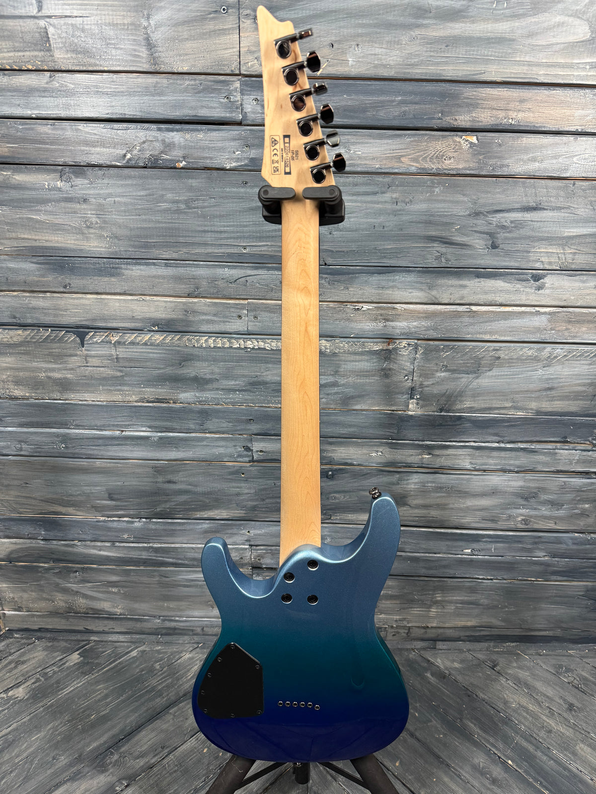 Blue electric guitar with a wooden neck against a wooden background