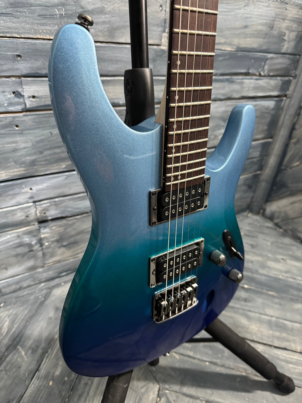 Blue electric guitar on a stand against a wooden background