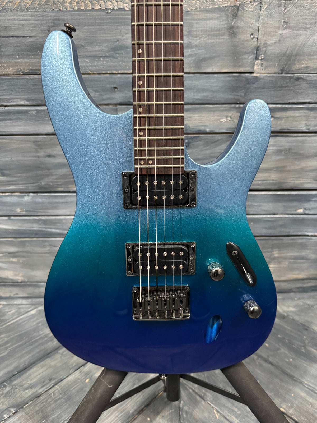 Blue electric guitar on a stand against a wooden background
