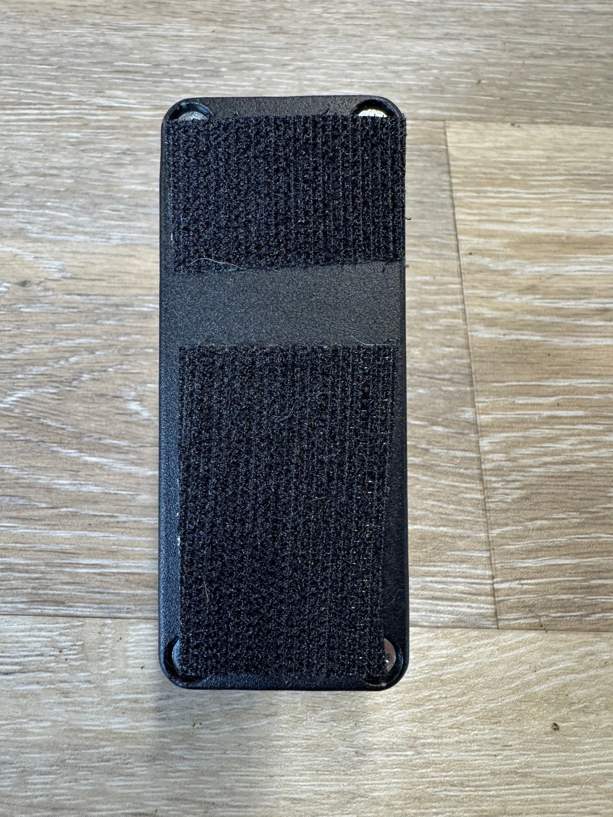 Black rectangular object with textured surface on a wooden floor