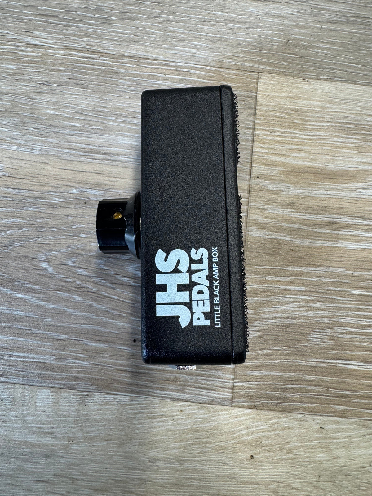 Black pedal with 'SHS' branding on a wooden surface
