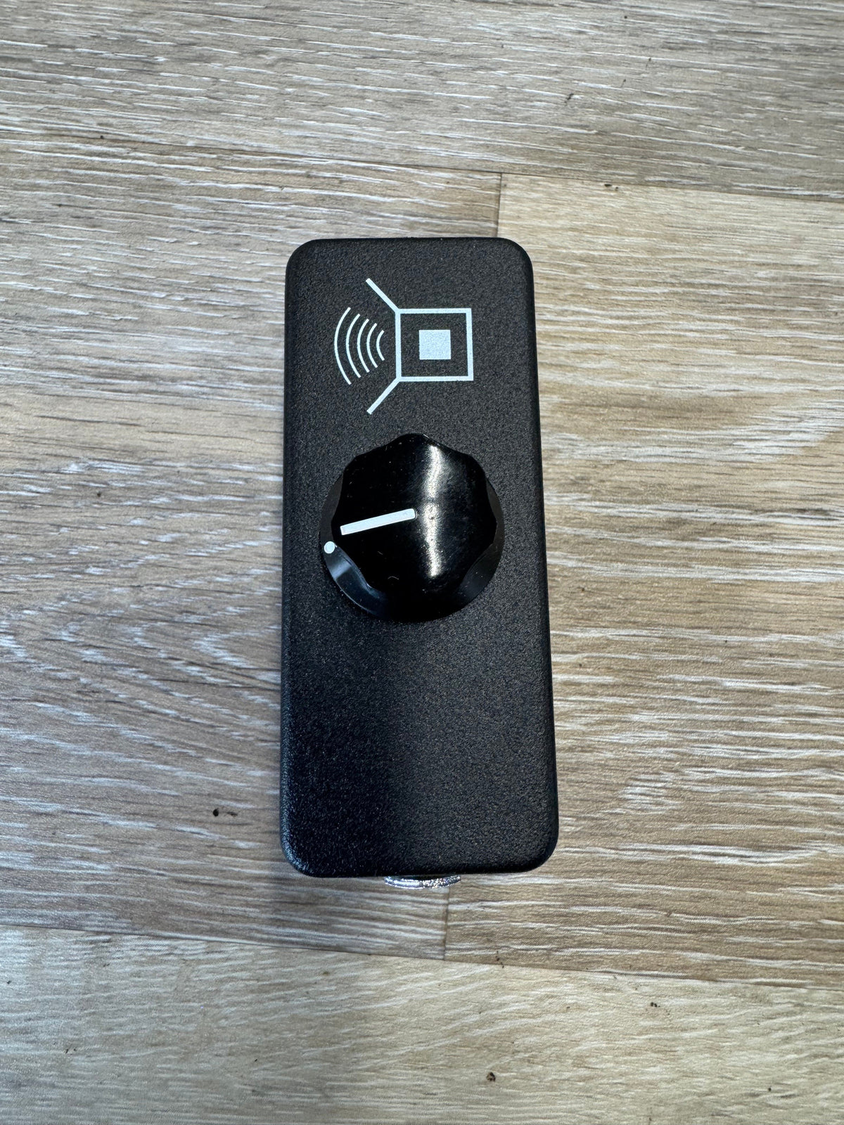 Black electronic device with a knob on a wooden surface