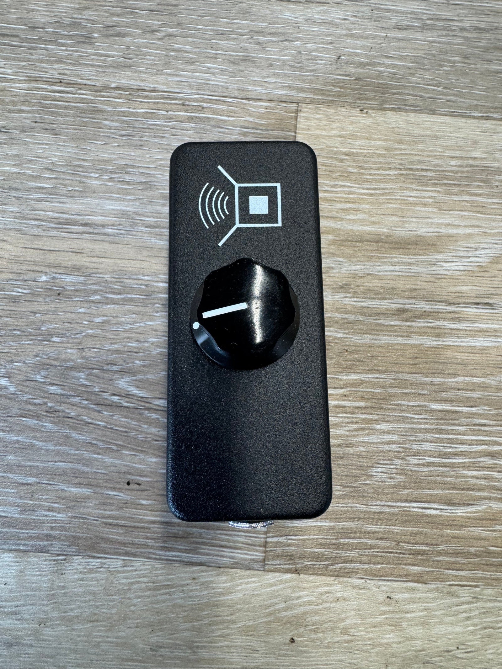 Black electronic device with a knob on a wooden surface