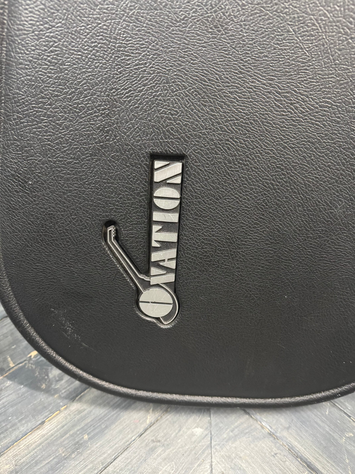 Black leather saddle pad with a brand logo on a wooden floor
