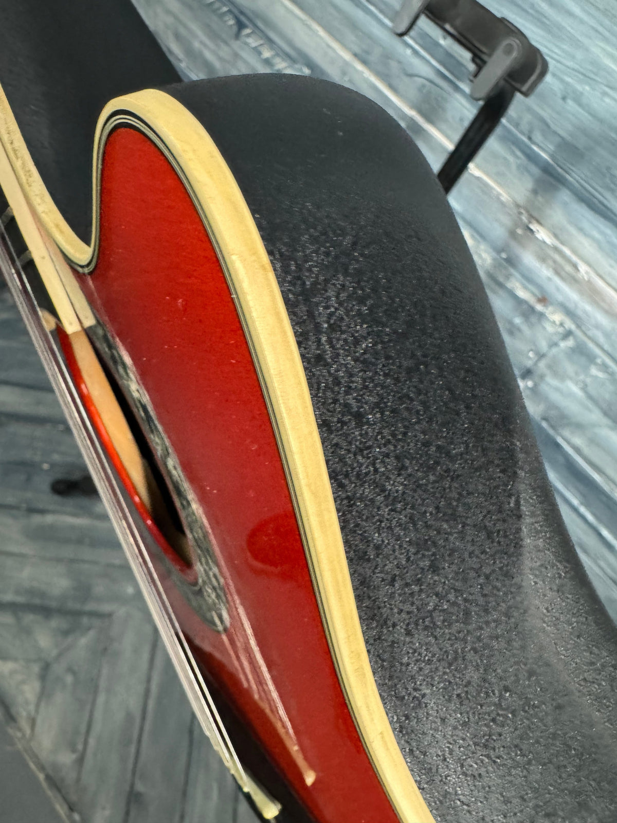 Close-up of a guitar with a red soundhole on a textured surface