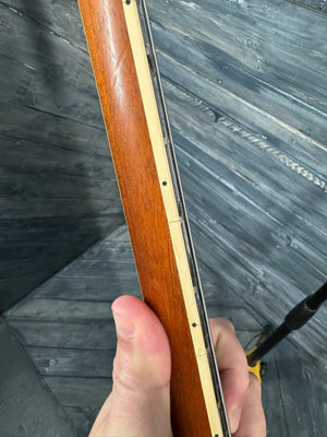 Hand holding a wooden object with a metallic edge against a textured gray background