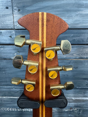 Wooden guitar headstock with tuning pegs against a wooden background