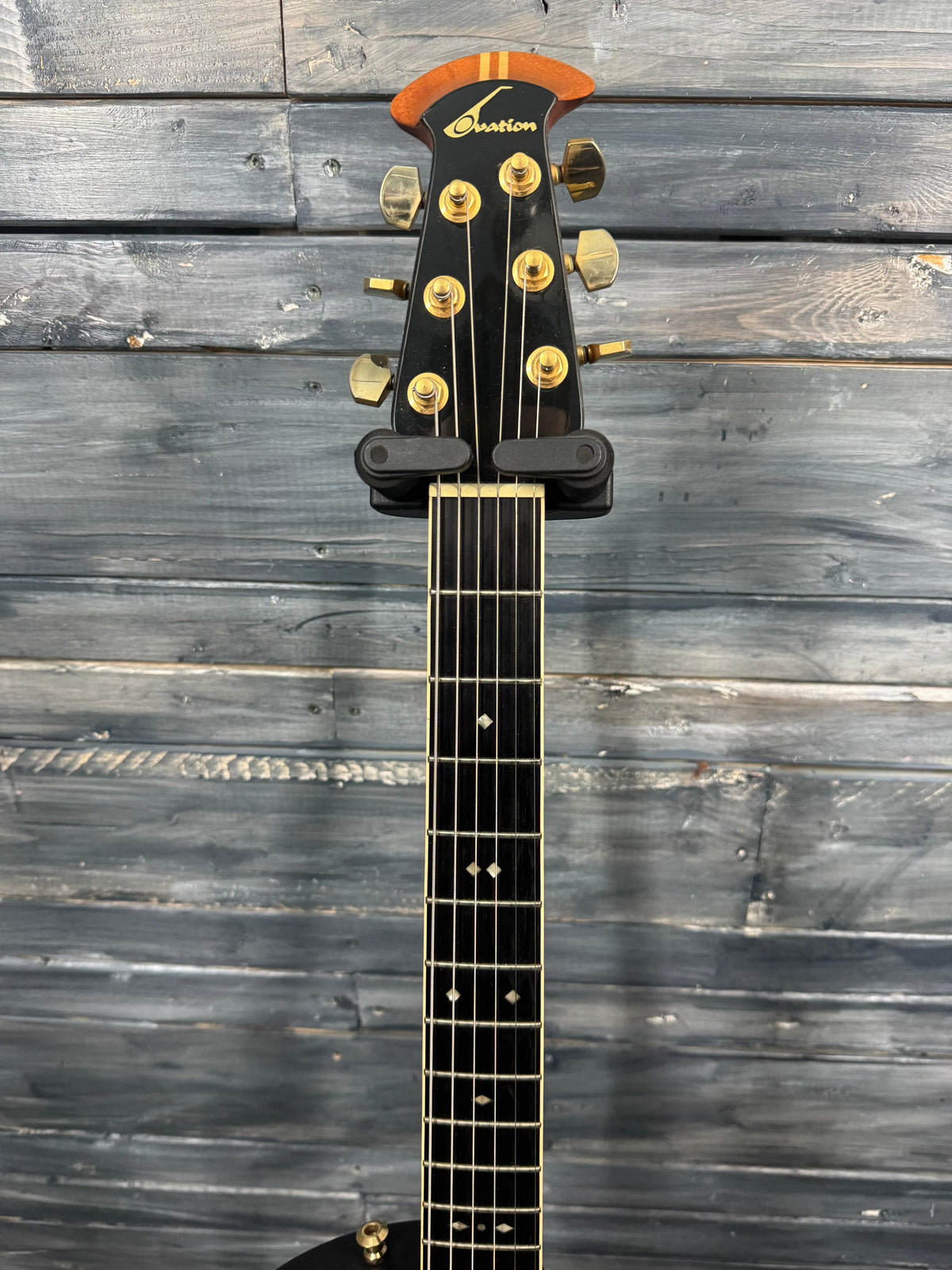 Guitar headstock with brand logo against a wooden background