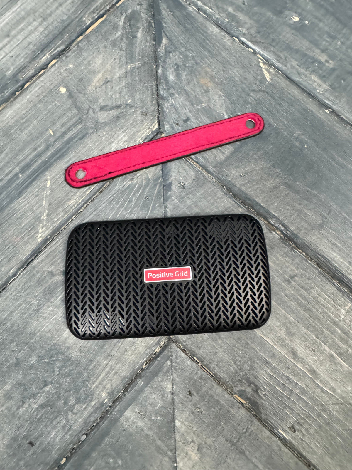 Black textured phone case with red tool on a gray stone surface
