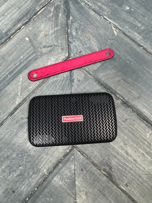 Black textured phone case with red tool on a gray stone surface