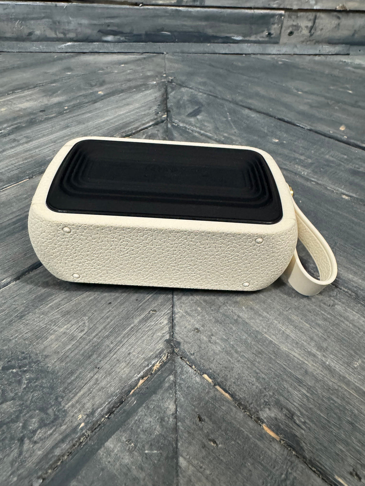 Beige portable speaker on a textured stone surface
