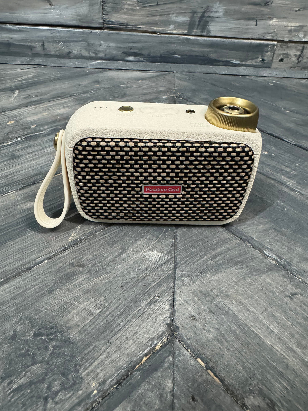 Portable speaker with textured surface and visible brand logo on a wooden floor.