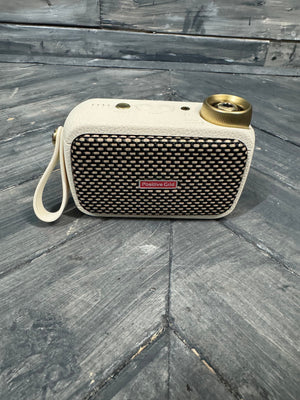 Portable speaker with textured surface and visible brand logo on a wooden floor.