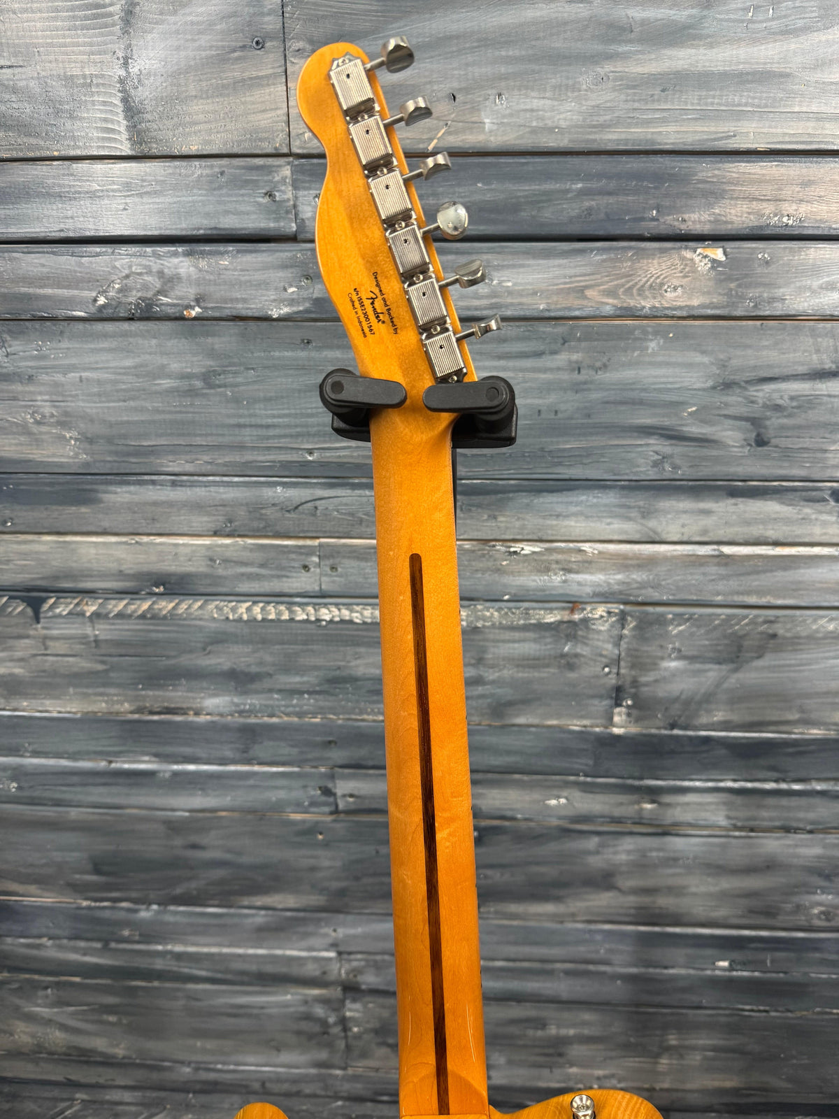 Electric guitar headstock against a wooden wall