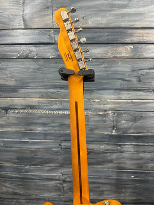 Electric guitar headstock against a wooden wall