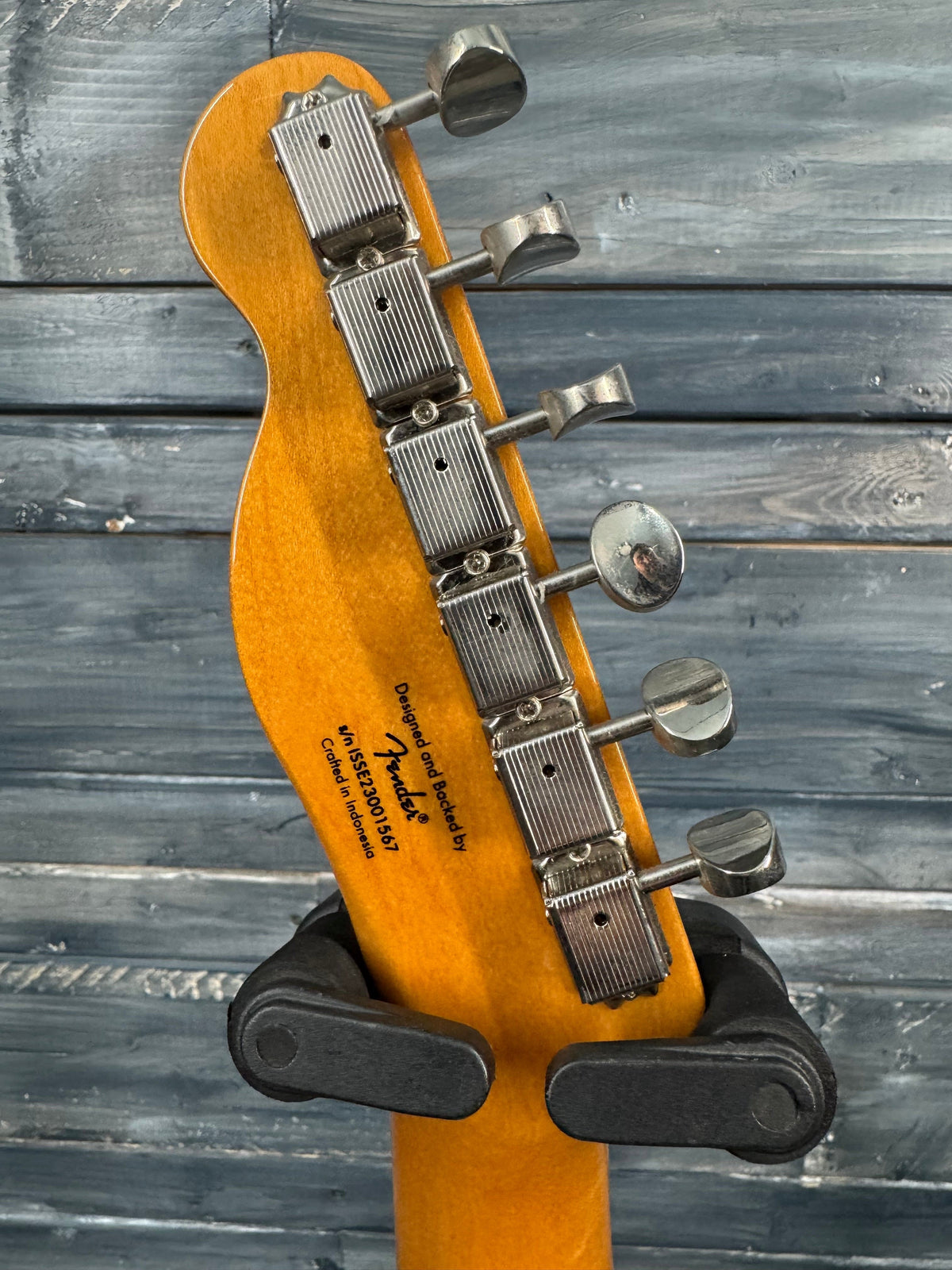 Guitar headstock with tuning pegs against a wooden background