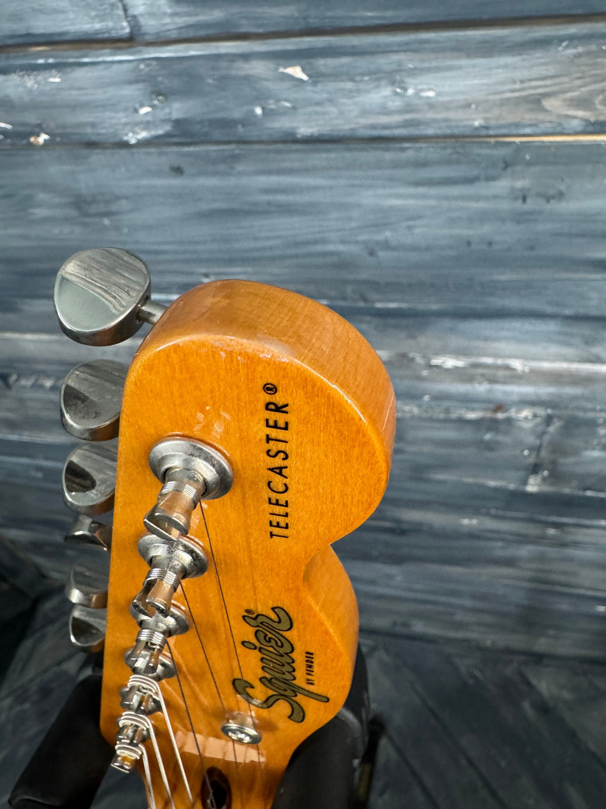 Close-up of a guitar headstock with 'Fender' branding against a wooden background