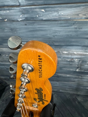 Close-up of a guitar headstock with 'Fender' branding against a wooden background