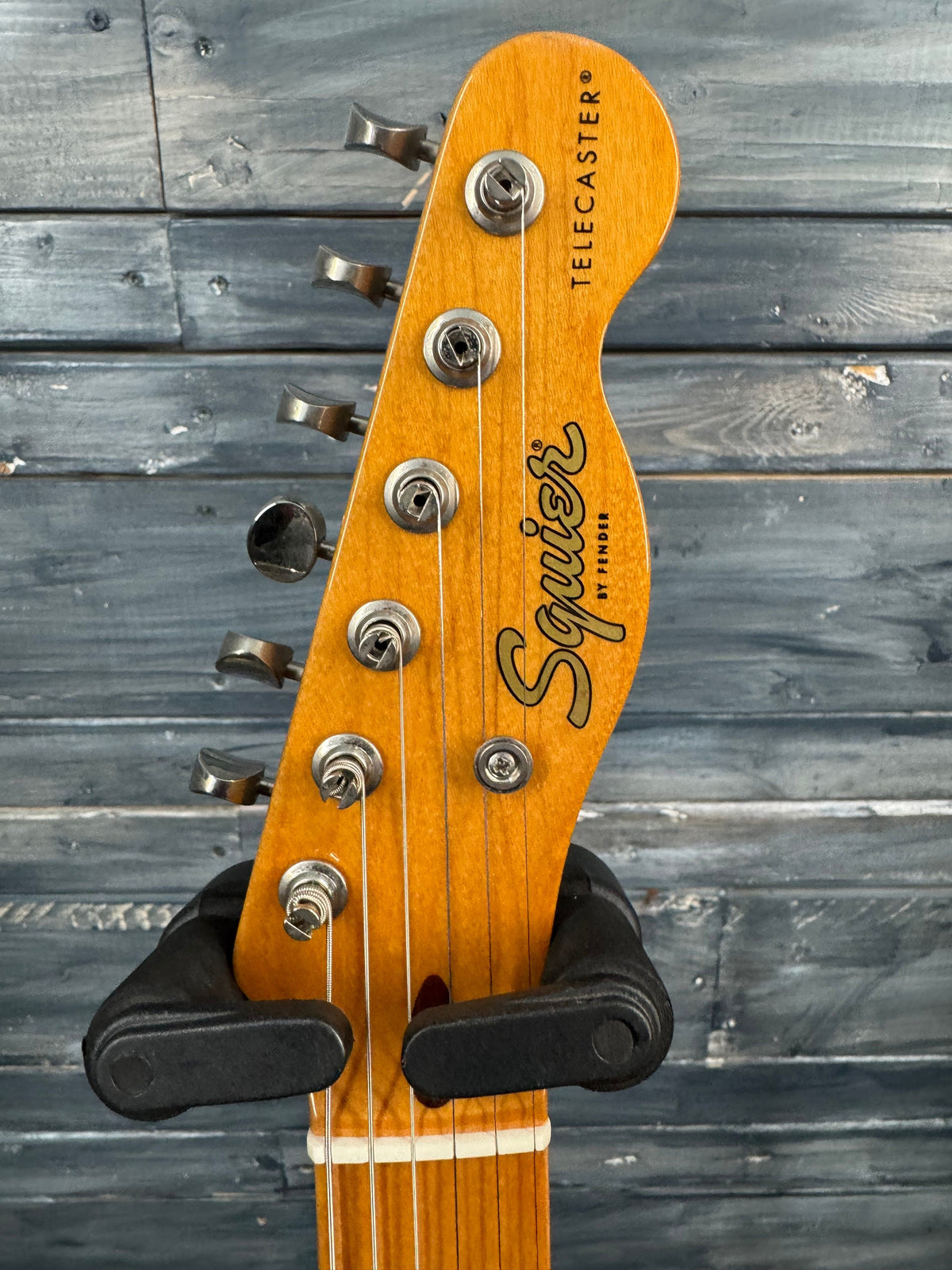 Guitar headstock with 'Square' branding against a wooden background