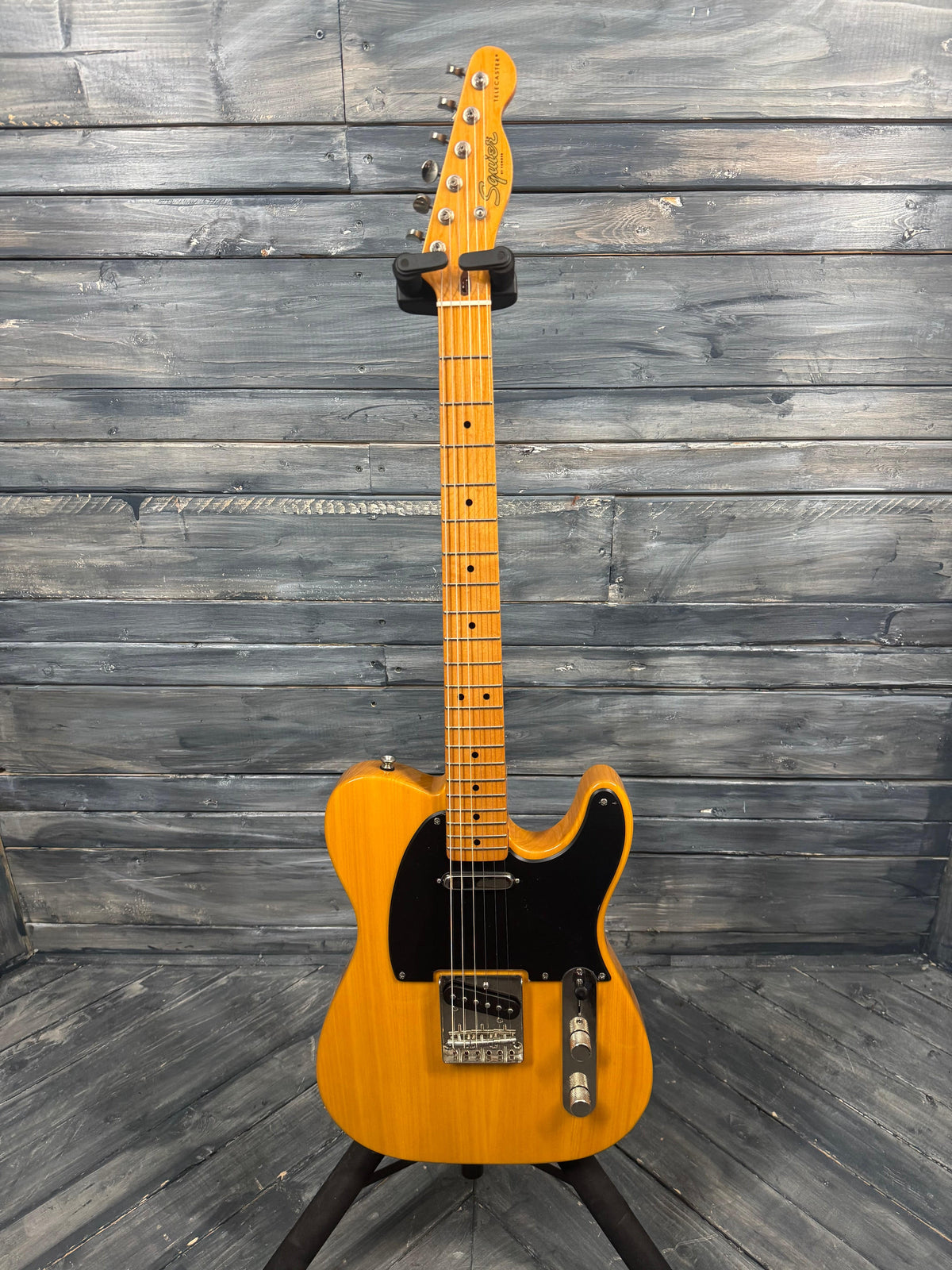 Electric guitar with a blonde finish against a wooden background