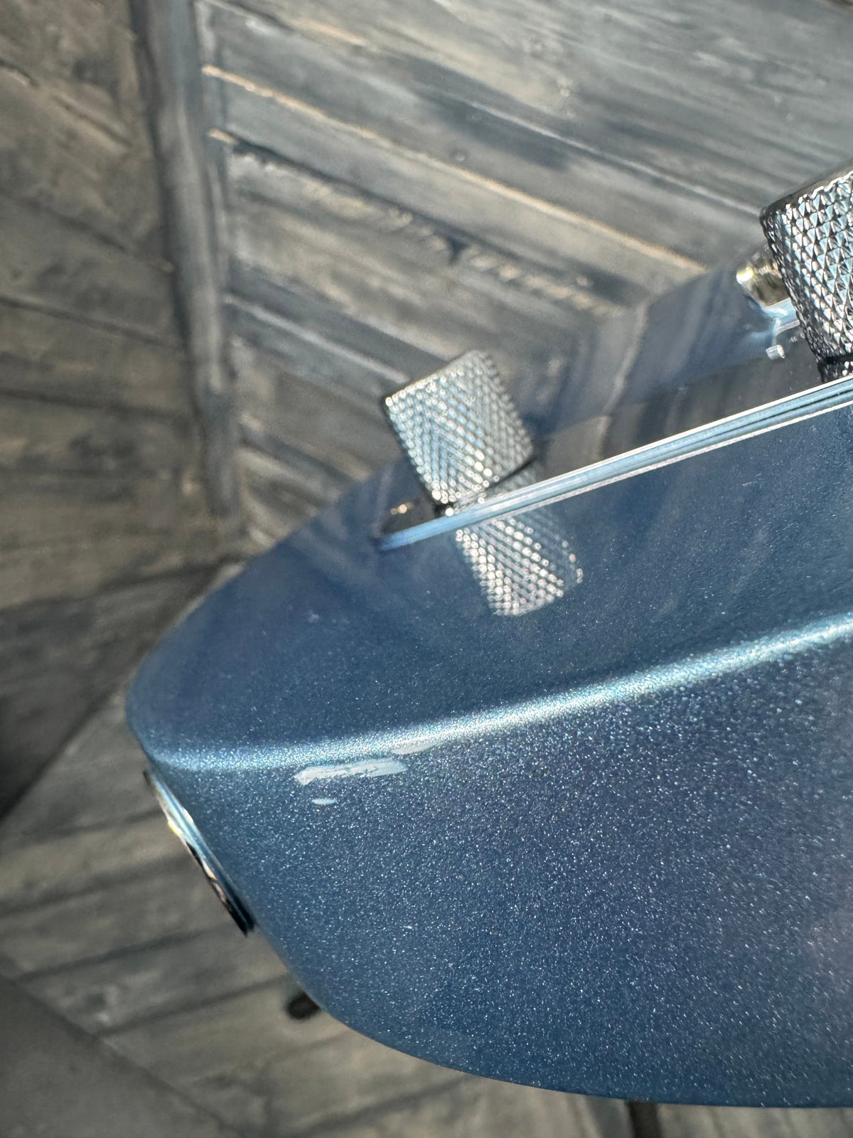 Close-up of a blue guitar case with metallic knobs on a wooden surface