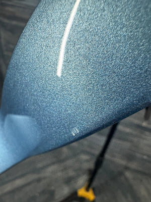 Close-up of a textured blue fabric surface with a white line and yellow object in the corner.