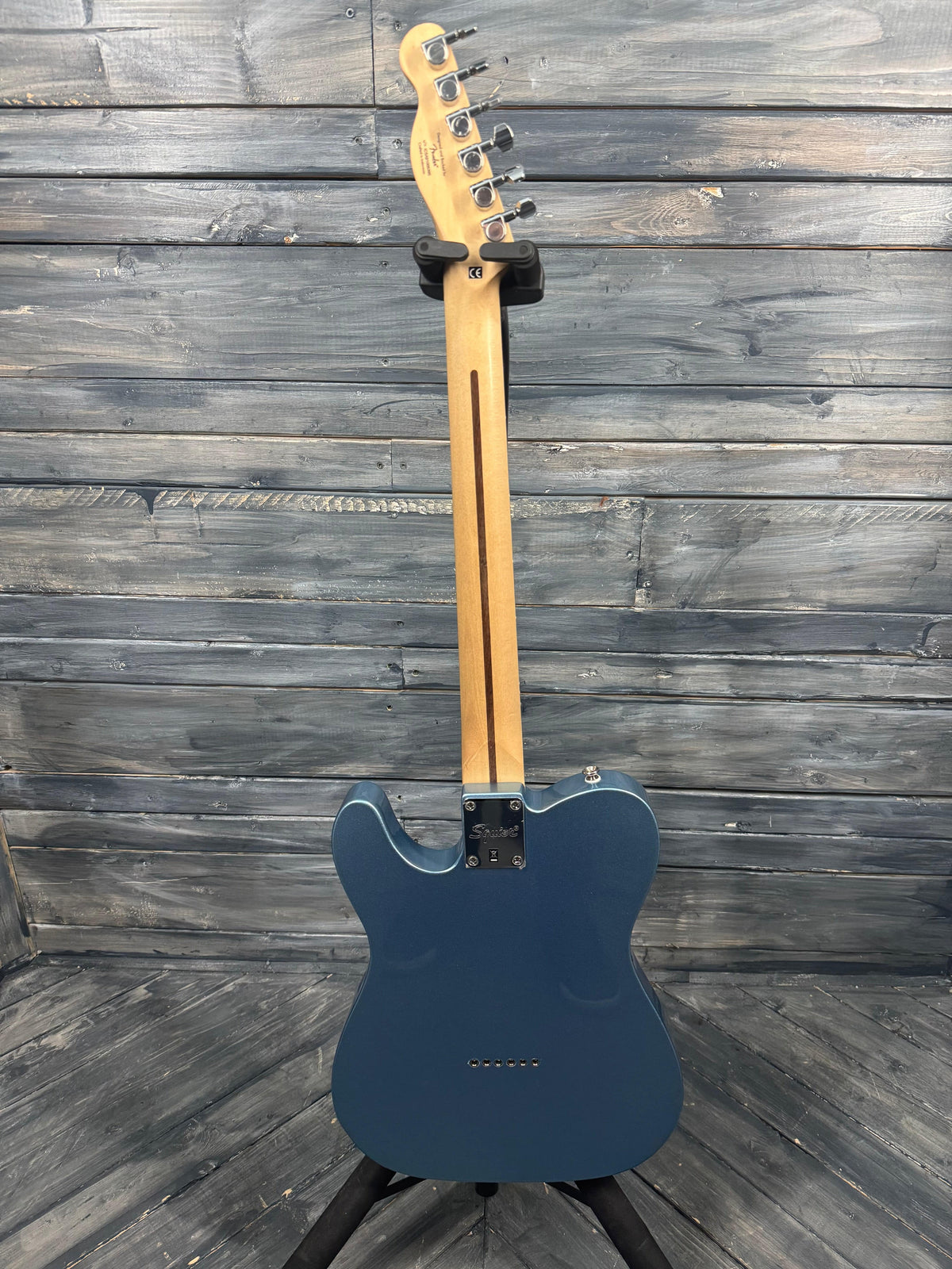 Blue electric guitar leaning against a wooden wall