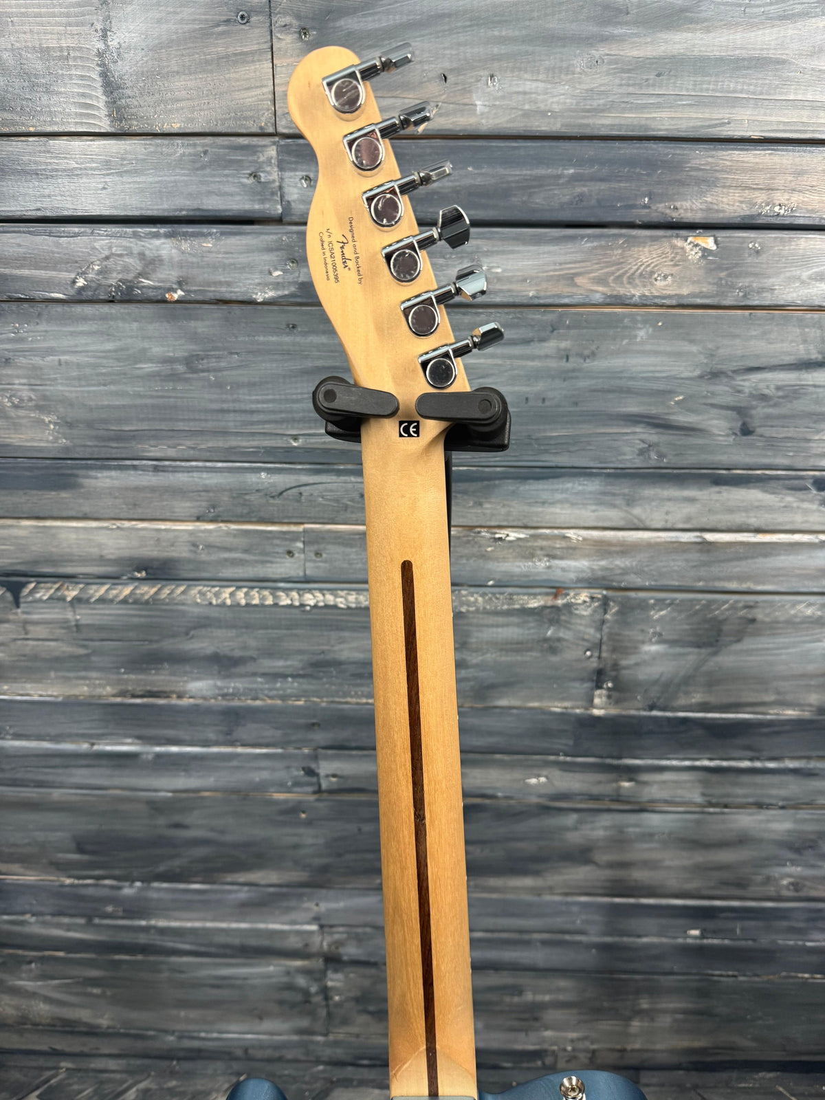 Fender bass guitar headstock against a wooden background