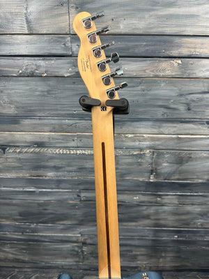 Fender bass guitar headstock against a wooden background