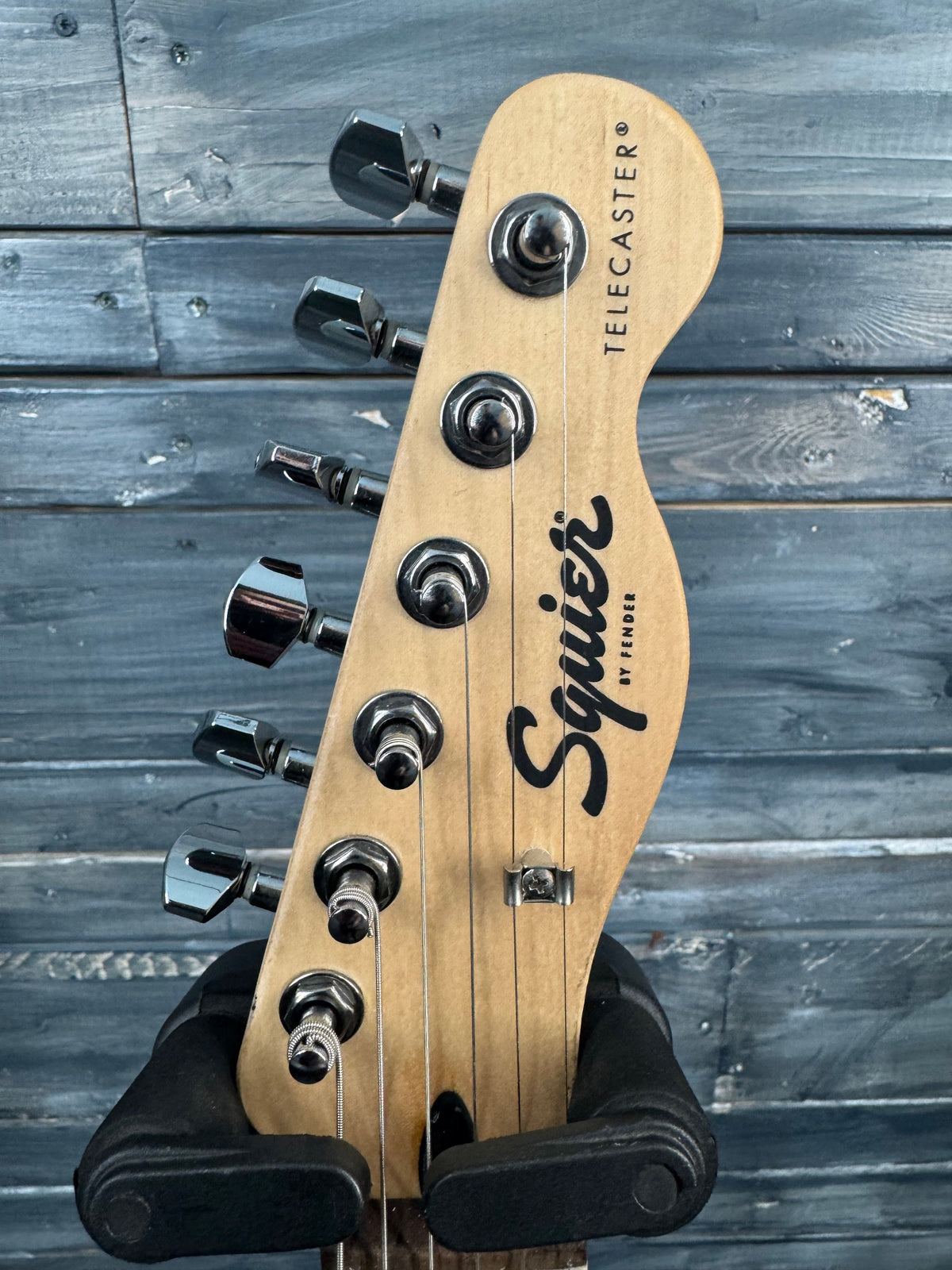 Fender Squier Telecaster guitar headstock against a wooden background