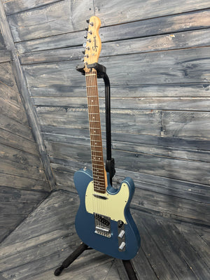 Blue electric guitar on a stand against a wooden background