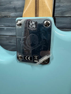 Close-up of a turquoise guitar with a clear cover displaying certification logos on a wooden background.