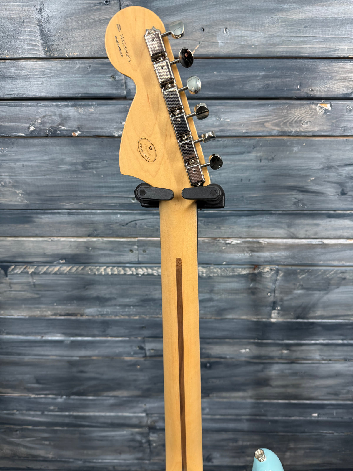 Guitar neck with headstock against a wooden background
