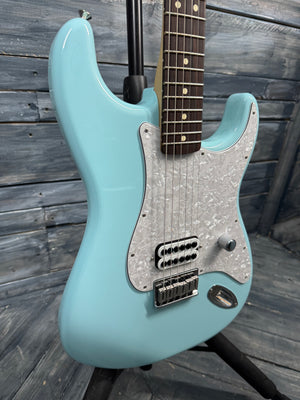 Electric guitar with a light blue body and silver pickguard against a wooden background