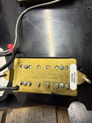 Gold guitar pickup with visible branding on a dark background
