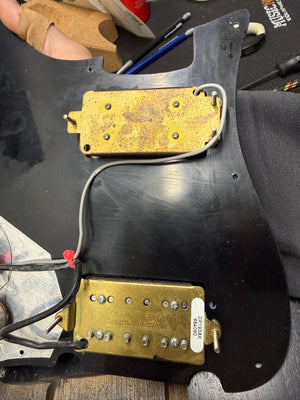 Guitar body with wiring and pickups on a workbench