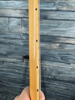 Wooden guitar neck held against a wooden background