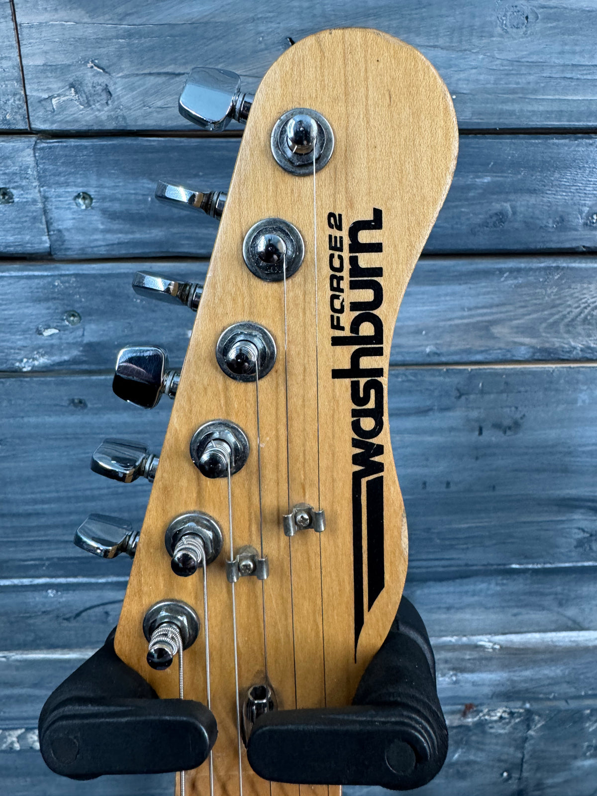 Guitar headstock with 'Washburn' branding on a wooden background