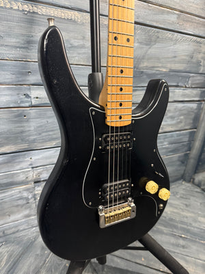 Black electric guitar with a wooden neck against a wooden background