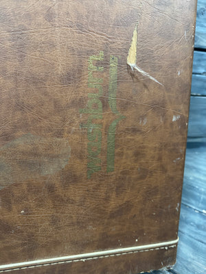 Brown leather-bound book with embossed logo on a wooden surface