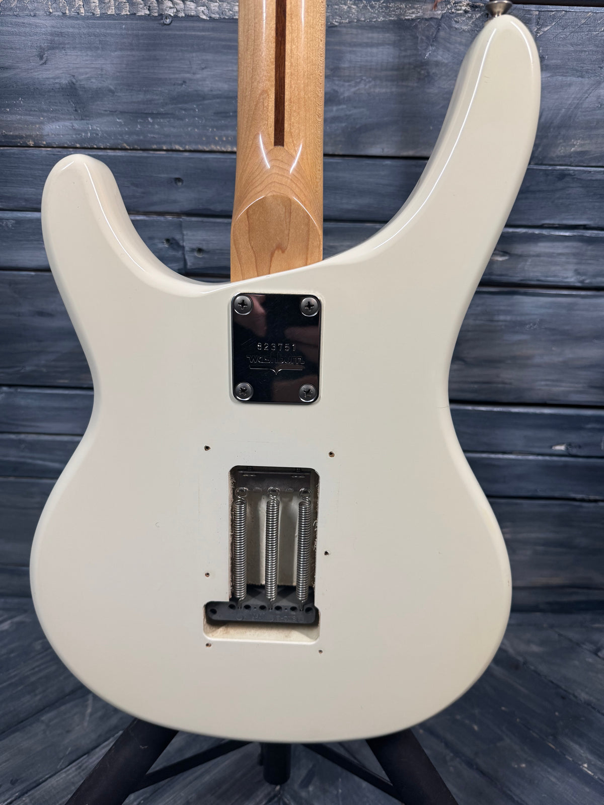 White electric guitar with a wooden neck against a wooden background