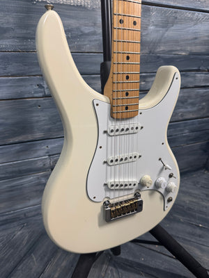 Beige electric guitar with a wooden fretboard against a wooden background