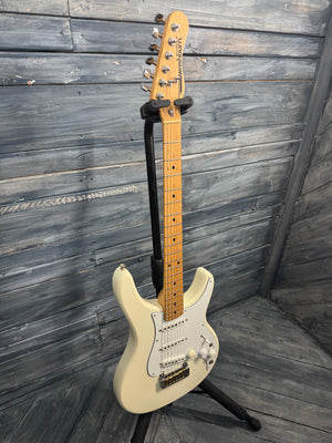 Beige electric guitar on a stand against a wooden wall.