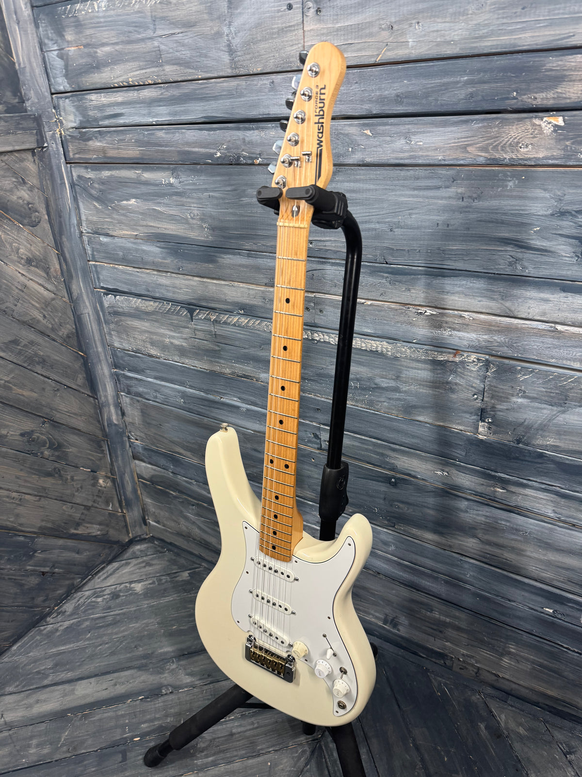 Electric guitar on a stand against a wooden wall