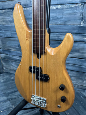 Wooden electric bass guitar against a wooden background