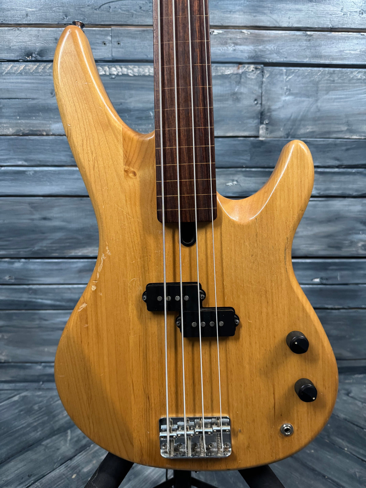 Wooden electric bass guitar against a wooden background
